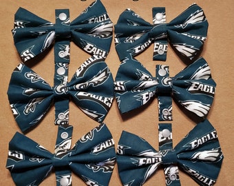 May include: Six green and white bow ties with a Philadelphia Eagles logo pattern. The bow ties have adjustable straps with snap closures.