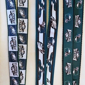 Puede incluir: Tres diferentes cordones de cinta verde y blanco con la palabra "Eagles" repetida en cada uno. Los cordones tienen aproximadamente 2,5 cm de ancho.