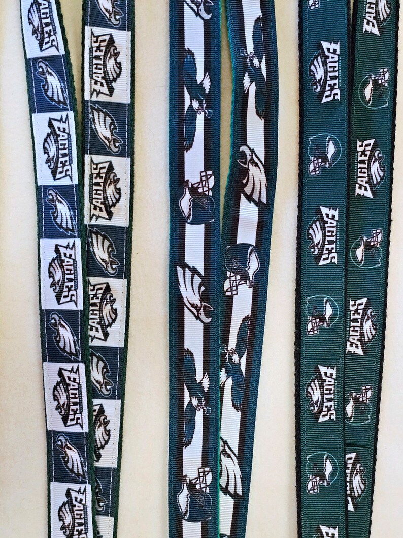 Puede incluir: Tres diferentes cordones de cinta verde y blanco con la palabra "Eagles" repetida en cada uno. Los cordones tienen aproximadamente 2,5 cm de ancho.