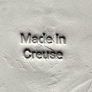 Peut inclure: Gros plan sur une surface en céramique blanche avec le texte "Made in Creuse" en relief sur la surface.