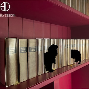 Könnte beinhalten: Ein weinrotes Bücherregal mit einer Reihe goldfarbener Bücher. Die Bücher haben ein strukturiertes Design und sind mit "Julien Green Oeuvres Completes" beschriftet. In der oberen linken Ecke steht der Text "Aubry Design".