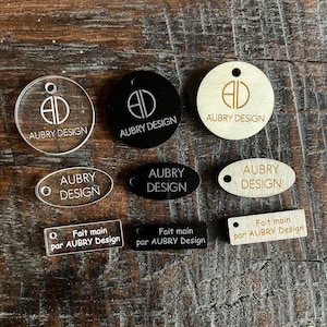 Puede incluir: Surtido de etiquetas ovaladas y redondas de madera y acrílico con el texto "AUBRY DESIGN" y "Fait main par AUBRY Design".