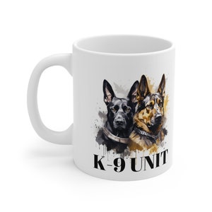 May include: White ceramic mug with a black and brown German Shepherd dog illustration. The dogs are looking at the viewer. The text "K-9 UNIT" is printed in black at the bottom of the mug.
