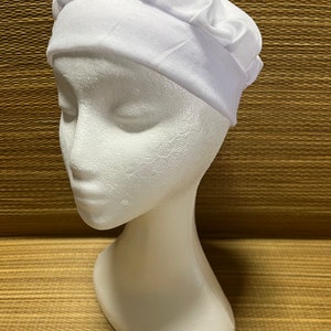 Pode incluir: Um turbante branco de algodão com o topo franzido.