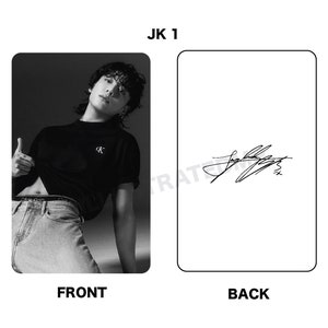 May include: Black and white photo card featuring a man wearing a black t-shirt with a white logo and blue jeans. The back of the card has a black and white signature.