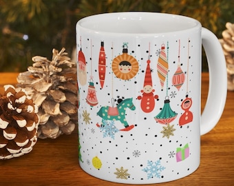 May include: White ceramic mug with a Christmas ornament design. The ornaments are colorful and include a rocking horse, a Santa Claus, and a snowman. The mug has a black handle.