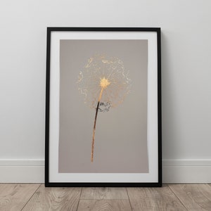 May include: A framed print of a gold dandelion on a grey background. The dandelion is a delicate, wispy flower with a golden centre.
