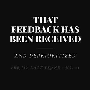 以下が含まれることがあります： 黒いポスターに白い文字で「THAT FEEDBACK HAS BEEN RECEIVED AND DEPRIORITIZED」と書かれています。その下に小さな文字で「PER MY LAST BRAND · NO. 01」とあります。メインのメッセージには太いセリフ体フォントが使用されています。