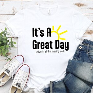 May include: White t-shirt with black text that reads "It's A Great Day to turn in all that missing work." A yellow sun graphic is above the text.