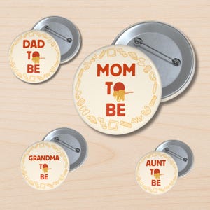 Puede incluir: Un conjunto de botones redondos de color crema con texto rojo y una ilustración de espaguetis. Los botones dicen "DAD TO BE", "MOM TO BE", "GRANDMA TO BE" y "AUNT TO BE". Cada botón tiene un reverso plateado y un borde de formas de pasta.