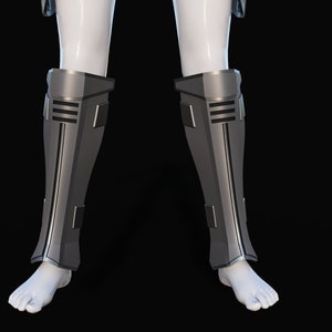May include: A pair of silver-colored shin guards with black accents. The guards are made of a hard material and have a sleek, futuristic design.