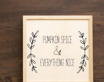 Peut inclure: Une pancarte en bois blanc avec une calligraphie noire qui dit "Pumpkin Spice & Everything Nice". Le texte est encadré par deux motifs floraux noirs.