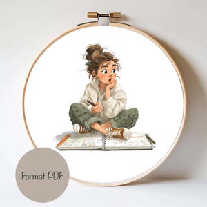 May include: A digital art print of a young person sitting cross-legged, holding a pencil, and looking thoughtful. The artwork is framed in a wooden embroidery hoop. The person is wearing a white jacket, green pants, and brown shoes. The text "Format PDF" is on a gray circle.