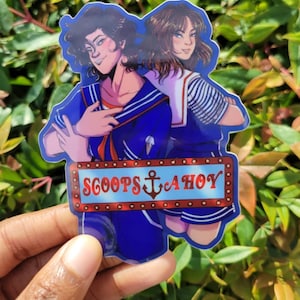 May include: A sticker featuring two cartoon characters in blue and white sailor outfits, standing in front of a red and white sign that reads "Scoops Ahoy".