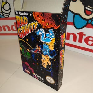 Puede incluir: Caja de videojuego vintage de "The Adventures of Rad Gravity". La caja presenta una colorida ilustración de un personaje con traje espacial sobre un fondo estrellado. El logotipo de Activision es visible.