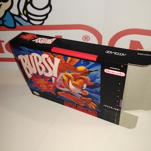 Puede incluir: Una caja de juego de Super Nintendo roja, blanca y azul con un personaje de dibujos animados llamado Bubsy. El juego se llama "Bubsy: The Claws Encounters of the Furred Kind".