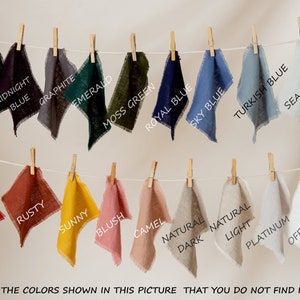 May include: Fabric swatches in various colors, including black, midnight blue, graphite, emerald, moss green, royal blue, sky blue, turquoise blue, sea glass, berry red, rusty, sunny, blush, camel, natural light, dark natural, platinum, and off white. The swatches are hanging on a clothesline with wooden clothespins.
