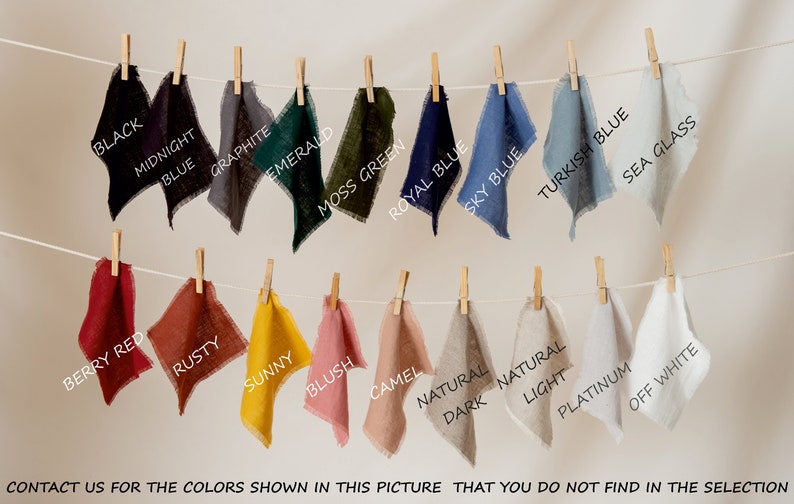 May include: Fabric swatches in various colors, including black, midnight blue, graphite, emerald, moss green, royal blue, sky blue, turquoise blue, sea glass, berry red, rusty, sunny, blush, camel, natural light, dark natural, platinum, and off white. The swatches are hanging on a clothesline with wooden clothespins.