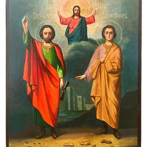 Può includere: Un'icona religiosa antica raffigurante tre figure. La figura centrale, Gesù, è raffigurata con le braccia aperte, circondato da un'aureola dorata. Due santi lo affiancano, uno con un bastone. L'opera è dipinta con colori vivaci, su sfondo scuro.