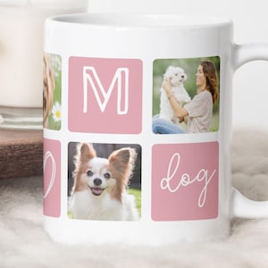 May include: White ceramic mug featuring a design with the word "MOM" and "dog" in a pink square. The mug includes photos of dogs and a person holding a dog. The mug has a white handle.