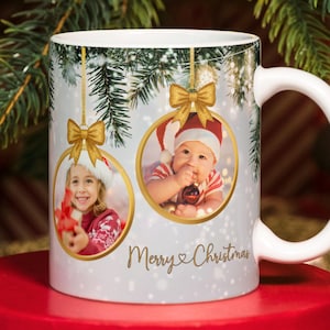 Peut inclure: Mug en céramique blanche avec un motif de Noël. Il présente deux ornements circulaires avec des photos d'enfants, des nœuds dorés et le texte "Merry Christmas". La tasse a une anse blanche et une scène hivernale.