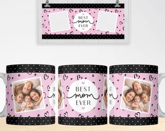 Puede incluir: Un diseño de sublimación para una taza con un fondo rosa con lunares negros y corazones. El diseño incluye un círculo con el texto "Best Mom Ever" en escritura negra. Hay dos portafotos en la taza.