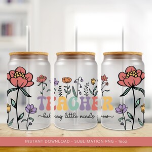 Puede incluir: Tres vasos transparentes de 470 ml con tapas de bambú y pajitas. Cada vaso presenta un diseño floral con una flor roja y la palabra "TEACHER" en colores arcoíris. El texto debajo dice "helping little minds grow".