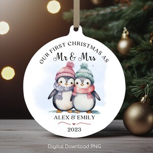 Puede incluir: Un adorno navideño redondo blanco con una pareja de pingüinos que llevan gorros y bufandas de invierno. El adorno dice "Nuestra primera Navidad como Sr. y Sra. Alex y Emily 2023".