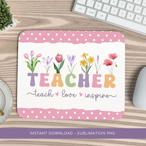 May include: A pink and white mouse pad with a white background and pink polka dots. The words "TEACHER teach love inspire" are written in colorful letters with a row of watercolor flowers above the text.