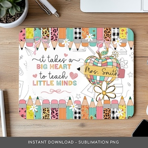 以下が含まれることがあります： 白い背景とカラフルな鉛筆の縁取りが付いた長方形のマウスパッド。「it takes a BIG HEART to teach LITTLE MINDS」というテキストと、「Mrs. Smith」という名前の鉛筆型のリンゴが特徴です。