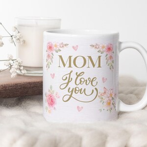 May include: White ceramic mug with a floral design and the text "MOM I love you" in gold lettering.