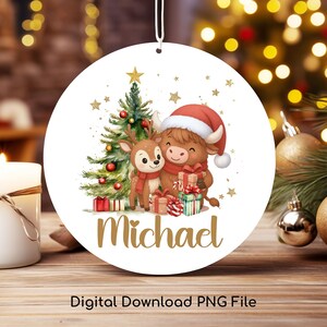 May include: A round Christmas ornament featuring a watercolor illustration of a reindeer and a Highland cow wearing Santa hats and scarves, with a Christmas tree and gifts. The name "Michael" is written in gold script. The text "Digital Download PNG File" is at the bottom.
