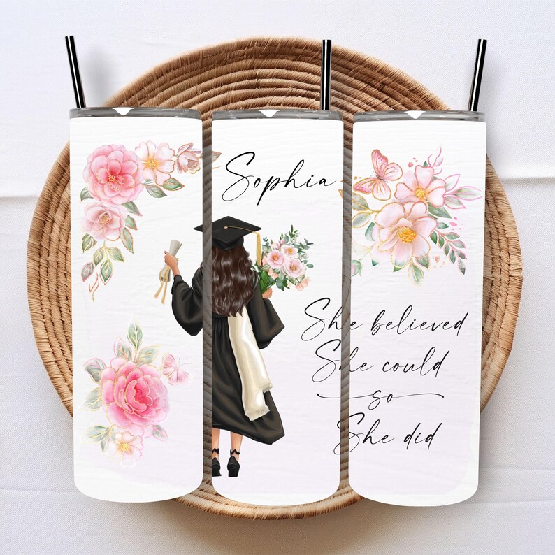 May include: Three white tumblers with a floral design and a graduation cap and gown illustration. The tumblers have the text "Sophia" and "She believed she could so she did" printed on them.