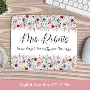 Può includere: Un tappetino per mouse rettangolare con un bordo floreale nei toni del rosa, blu e viola. Il tappetino presenta il testo "Mrs. Roberts" in elegante scrittura, con la frase "Never Forget the Difference You Make" sotto.