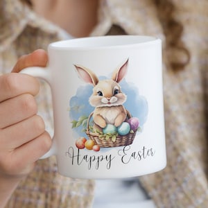 May include: White ceramic mug with a cartoon bunny holding Easter eggs in a basket. The mug has the text "Happy Easter" printed on it.