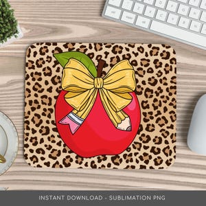 May include: A red apple with a yellow bow and two pencils on a leopard print background. The apple is a symbol of education and the pencils represent learning.