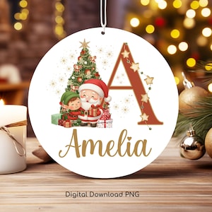 Puede incluir: Un adorno navideño redondo con Papá Noel y un elfo junto a un árbol de Navidad decorado. La letra "A" está adornada con estrellas, y el nombre "Amelia" está escrito en escritura dorada. Las palabras "Digital Download PNG" están en la parte inferior.