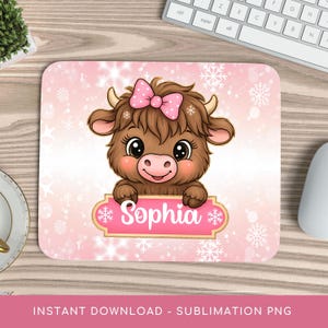 May include: A personalized mousepad featuring a cartoon Highland cow with a pink bow and the name "Sophia" on a pink banner. The background has a pink gradient with white snowflakes. The mousepad is rectangular.
