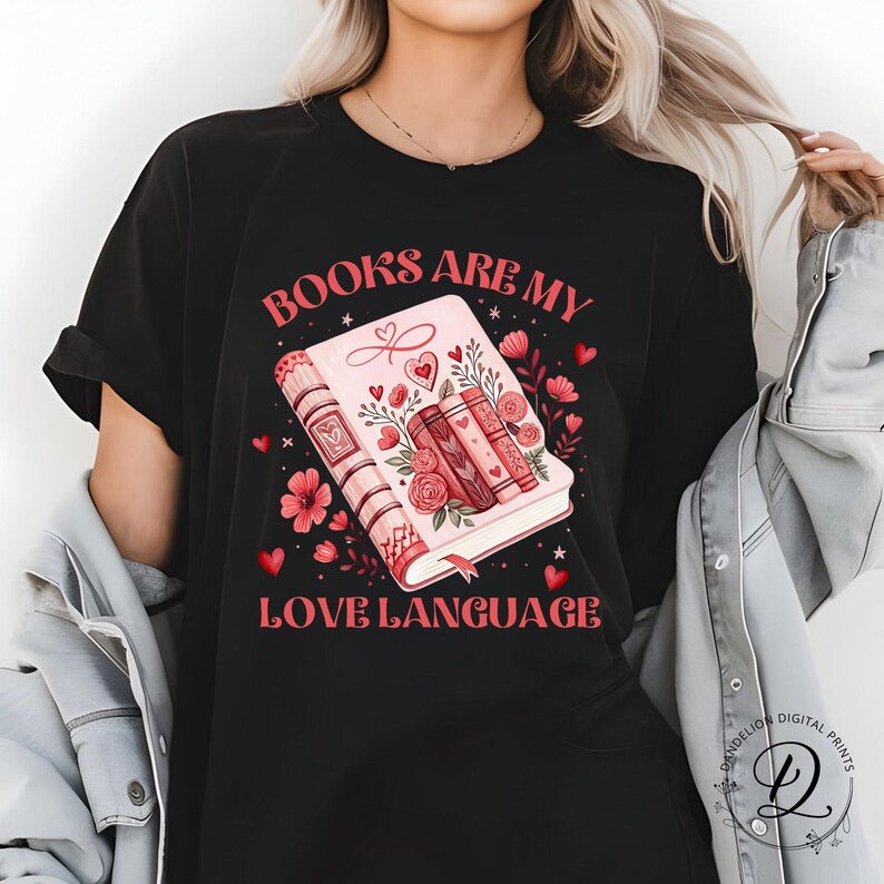 May include: Black t-shirt with the slogan "BOOKS ARE MY LOVE LANGUAGE" in red. The graphic shows a pink book with floral and heart details, and three stacked books. Ideal for book enthusiasts.