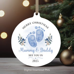 Pode incluir: Ornamento de Natal redondo branco com pegadas de bebê azuis em aquarela, detalhes florais e o texto "Feliz Natal Mamãe e Papai Nos vemos em 2025".