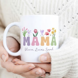 May include: White ceramic mug with the word "MAMA" in pastel colors with flowers in each letter. The names Olivia, Lucas, and Sarah are written below the word "MAMA".