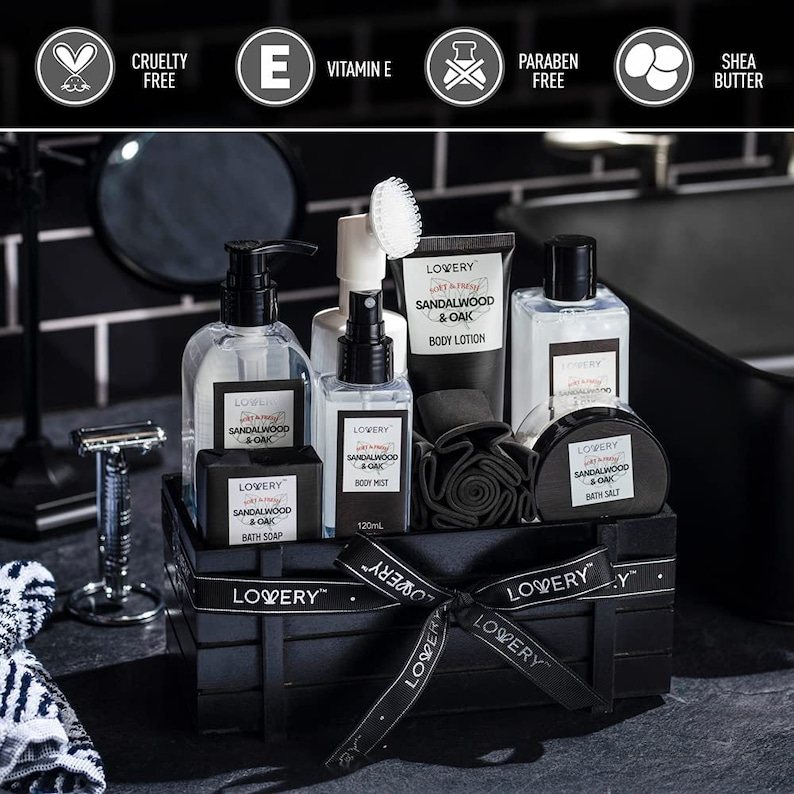May include: A black wooden crate filled with bath and body products. The products include bottles, a bar of soap, and a jar, all labeled "Sandalwood & Oak" by LOVERY. A black ribbon with the LOVERY logo is tied around the crate. The image also includes a razor and a washcloth.