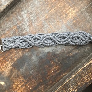 May include: Gray crocheted pacifier clip with a silver clip. The clip is attached to a gray crocheted cord with a tassel at the end.