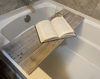 May include: A wooden bath tray with a book and a glass of wine on top. The tray is made of reclaimed wood and has a rustic look.