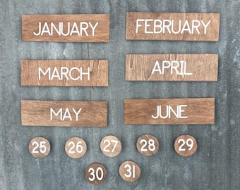 May include: Wooden calendar pieces with white lettering. Rectangular pieces spell out the months January, February, March, April, May, and June. Round pieces display the numbers 25, 26, 27, 28, 29, 30, and 31.