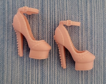 Puede incluir: Un par de zapatos de tacón alto rosa con correas de tobillo. Los zapatos tienen una plataforma y un diseño decorativo en la parte delantera.