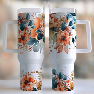 Peut inclure: Gobelet blanc avec un motif floral compos&eacute; de fleurs et de feuilles aquarelles orange, sarcelle et vertes. Le gobelet a une poign&eacute;e transparente et un couvercle transparent avec une paille.