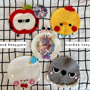 May include: A collection of handmade crochet coasters in various designs. Includes a red apple, yellow chick, white bunny, white creature, and gray creature. The coasters are round and feature cartoon-like faces. The text "Love and Deepspace" and "Crochet Coasters" are also visible.
