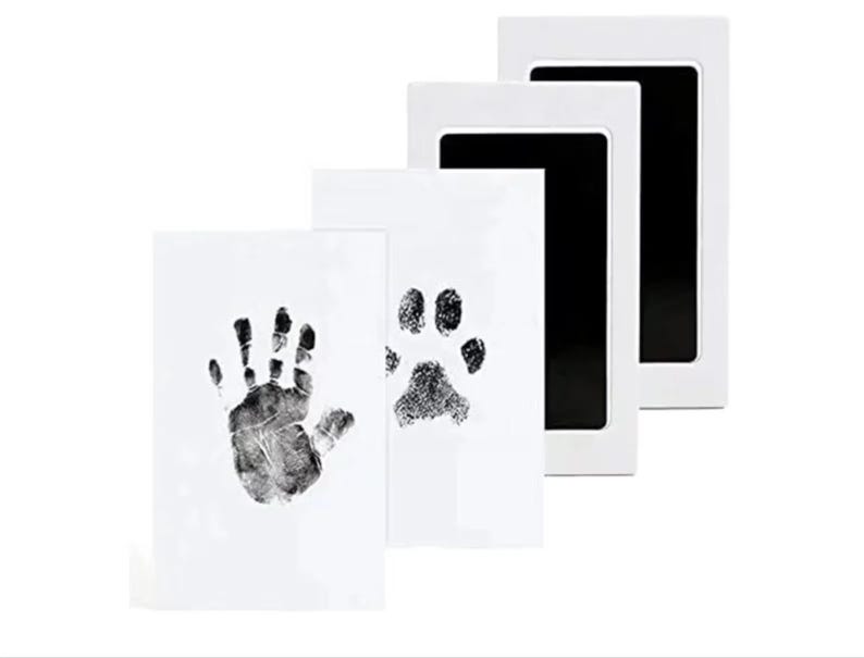May include: Three white ink pads with black ink wells. The ink pads are for making handprints and paw prints.