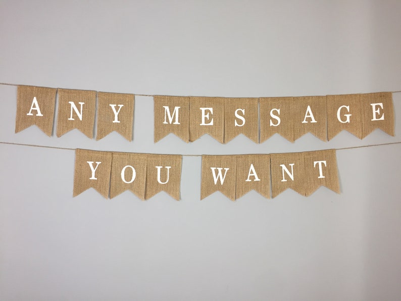 Peut inclure: Une banni&egrave;re en toile de jute avec le texte "ANY MESSAGE YOU WANT" en lettres blanches. La banni&egrave;re est suspendue &agrave; un mur blanc.